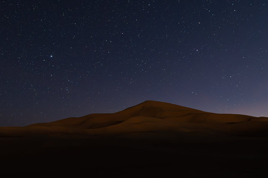 Dunas de areia sob um céu estrelado, simbolizando o misticismo do deserto e a busca pelo tesouro em O Alquimista.