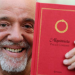 Paulo Coelho segurando seu livro O Alquimista.