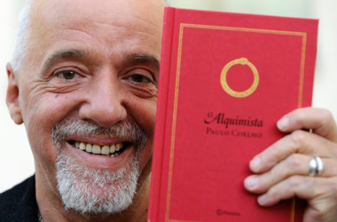 Paulo Coelho segurando seu livro O Alquimista.